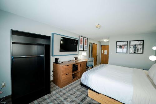 a hotel room with a bed and a desk and a tv at AmericInn by Wyndham Tomahawk in Tomahawk