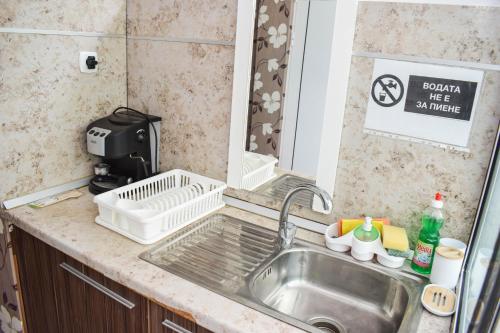 a kitchen sink with a dish drying rack next to it at Стаи за гости Люляк 21 in Pavel Banya