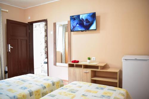 a bedroom with a bed and a television on the wall at Стаи за гости Люляк 21 in Pavel Banya