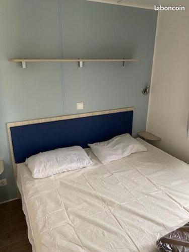- un lit avec une tête de lit bleue et 2 oreillers blancs dans l'établissement Mobil-home 6 personnes - Camping La Falaise 4* / Piscine / Club enfants / SPA / Restaurant / Animations, à Narbonne