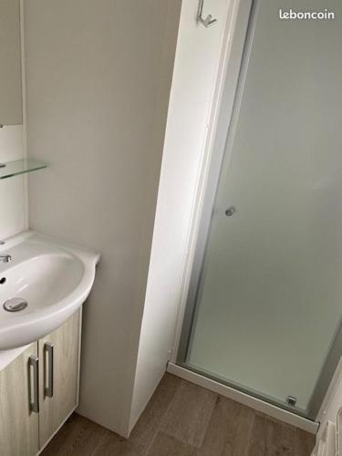 une salle de bain blanche avec un lavabo et une douche dans l'établissement Mobil-home 6 personnes - Camping La Falaise 4* / Piscine / Club enfants / SPA / Restaurant / Animations, à Narbonne