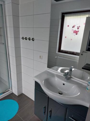 een badkamer met een witte wastafel en een raam bij Schöner Weitblick in Bad Sachsa