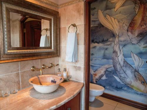 a bathroom with a sink and a painting on the wall at Wild Horses Lodge in Harrismith