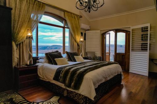 una camera da letto con un grande letto con una grande finestra di Wild Horses Lodge a Harrismith