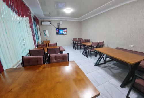 a dining room with tables and chairs and a tv at Hostel Sulaiman-Too in Osh