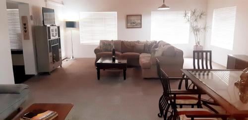 a living room with a couch and a table at Shark Cove House in Kleinbaai