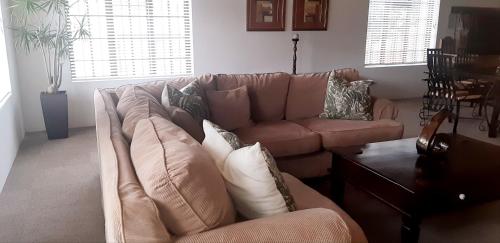 a living room with a brown couch and a table at Shark Cove House in Kleinbaai