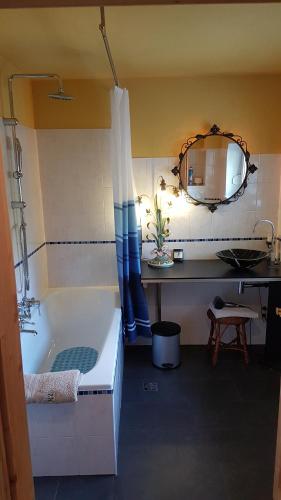 a bathroom with a tub and a sink and a mirror at Highland Accommodation Bavaria in Weilheim in Oberbayern