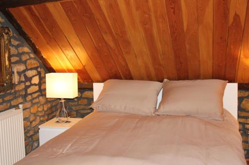 Bett mit einem Kopfteil aus Holz und einer Lampe in der Unterkunft Le Moulin in Matton-et-Clémency
