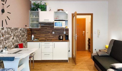 une cuisine avec des placards blancs et un salon dans l'établissement Apartmán Nikol Lipno nad Vltavou, à Lipno nad Vltavou