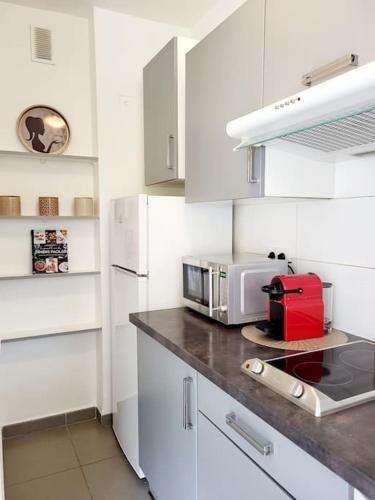 - une cuisine blanche avec un comptoir et un four micro-ondes dans l'établissement Cosy Studio à Cannes 8 min de la Croisette, à Cannes