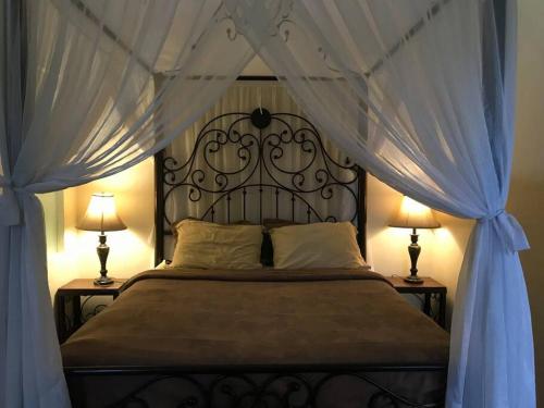 um quarto com uma cama preta com cortinas e 2 candeeiros em Bale Pari em Mataram