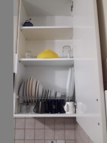 a kitchen cabinet with plates and utensils at Nicosia City Centre Apartment in Nicosia