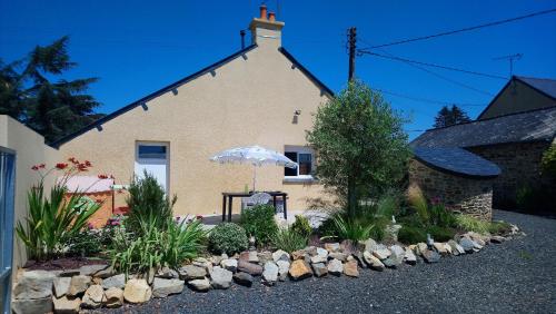 a building with an umbrella in front of a garden at Gîte Des Huttes in Bain-de-Bretagne