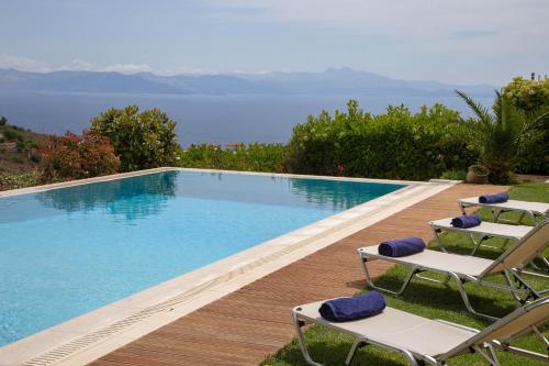 a swimming pool with chairs and the ocean in the background at Villa Marina, Sea View Luxury Villa in Mati