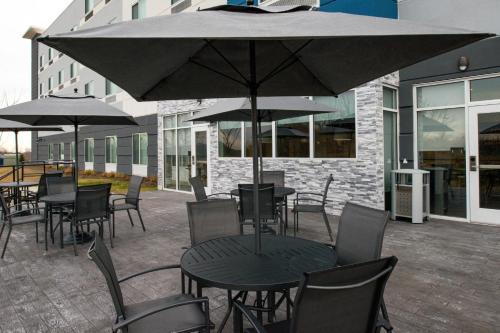 a patio with tables and chairs and an umbrella at Fairfield Inn & Suites by Marriott Charlotte University Research Park in Charlotte
