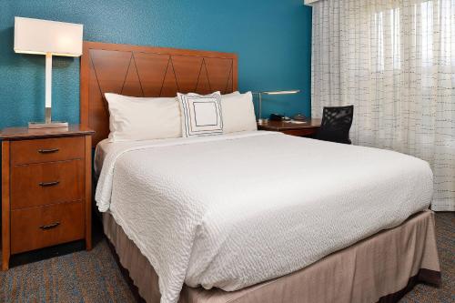 a bedroom with a large white bed and a nightstand at Residence Inn by Marriott Denver Airport at Gateway Park in Aurora