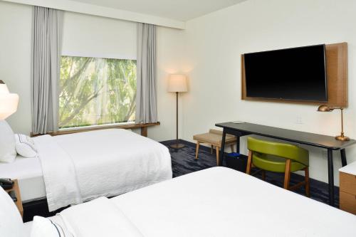 um quarto de hotel com duas camas e uma secretária com uma televisão em Fairfield Inn & Suites by Marriott Charlotte University Research Park em Charlotte