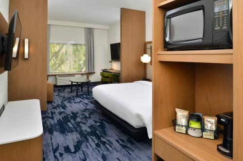 a hotel room with a bed and a tv at Fairfield Inn & Suites by Marriott Charlotte University Research Park in Charlotte