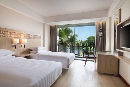 a hotel room with two beds and a flat screen tv at Fairfield by Marriott Bali Legian in Legian