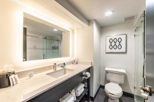 a bathroom with a sink and a toilet and a mirror at Four Points by Sheraton Greensboro Airport in Greensboro