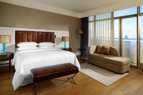 a bedroom with a large white bed and a chair at Sheraton Grand Adana in Adana