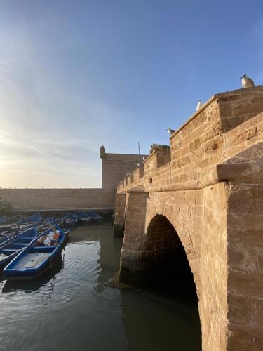an old stone bridge with boats in the water at Riad Eucalyptus by Caravanserail in Essaouira