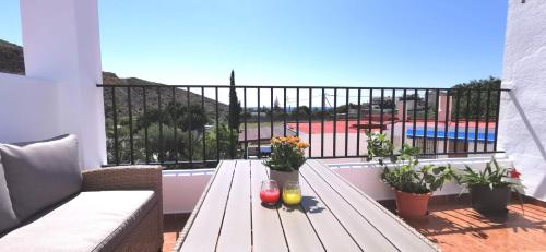 een balkon met een houten tafel met 2 drankjes erop bij Vistas mar y montaña LasNegras in Las Negras
