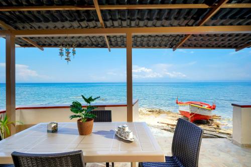 una mesa y sillas con vistas al océano en To Kyma - Seafront House, en Skala Kallirakhis