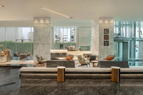 a hotel lobby with a large bed and chairs at Le Meridien Bangkok in Bangkok