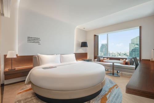 a bedroom with a large white bed and a living room at Le Meridien Bangkok in Bangkok