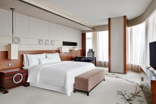 a bedroom with a large white bed and a television at The Westin Pazhou in Guangzhou