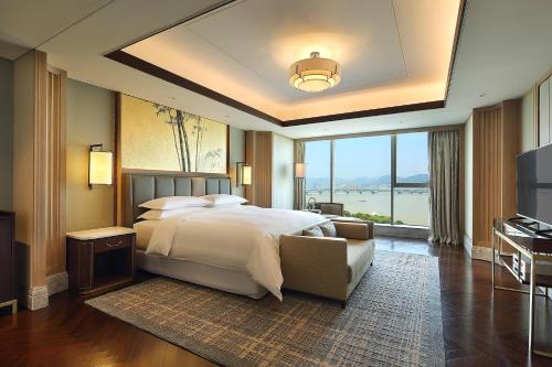 a bedroom with a large bed and a large window at Sheraton Grand Hangzhou Binjiang Hotel in Hangzhou