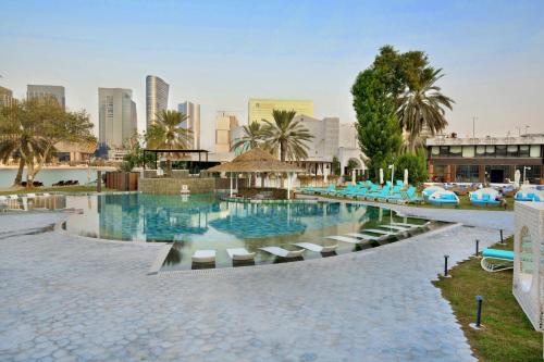a large swimming pool with lounge chairs and a city at Le Meridien Abu Dhabi Resort in Abu Dhabi