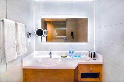 a white bathroom with a sink and a mirror at Le Meridien Abu Dhabi Resort in Abu Dhabi