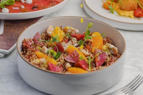a bowl of food on a table with plates of food at Le Meridien Abu Dhabi Resort in Abu Dhabi