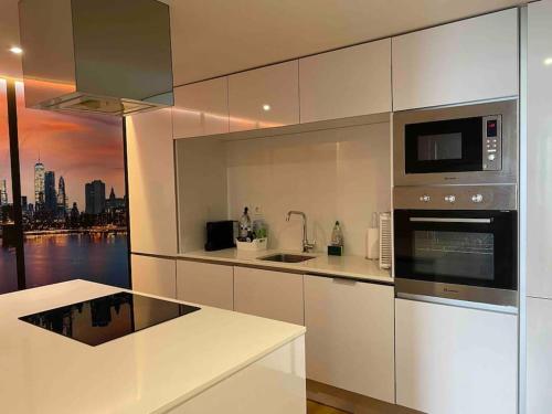 una cucina bianca con vista sulla città di Lisbon South Bay modern apartment with river view ad Almada