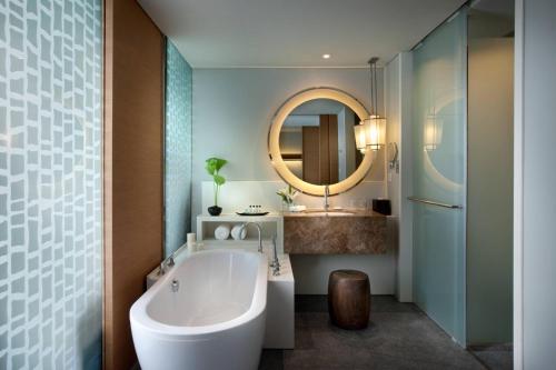 a bathroom with a tub and a sink and a mirror at Rayong Marriott Resort & Spa in Klaeng