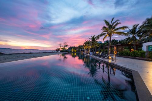 - une piscine sur la plage avec un coucher de soleil dans l'établissement Rayong Marriott Resort & Spa, à Klaeng