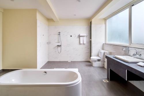 a bathroom with a tub and a toilet and a sink at Protea Hotel by Marriott Kampala Skyz in Kampala