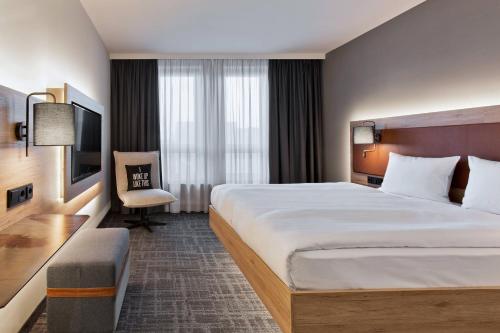 ein Hotelzimmer mit einem großen Bett und einem Stuhl in der Unterkunft MOXY Berlin Humboldthain Park in Berlin