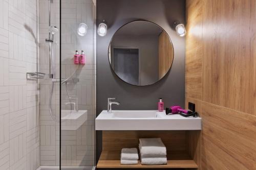 a bathroom with a sink and a shower with a mirror at MOXY Berlin Humboldthain Park in Berlin