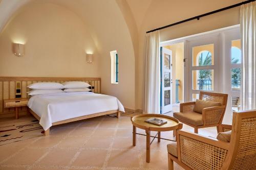 a bedroom with a bed and a chair and a table at Sheraton Miramar Resort El Gouna in Hurghada