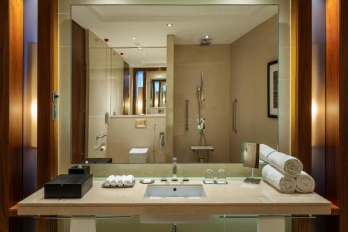 La salle de bains est pourvue d'un lavabo et d'un grand miroir. dans l'établissement JW Marriott Marquis Hotel Dubai, à Dubaï