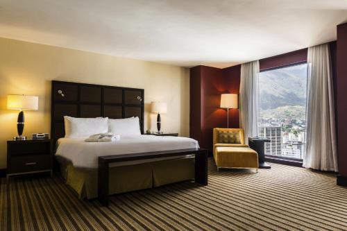 Pokój hotelowy z łóżkiem, krzesłem i oknem w obiekcie Renaissance Caracas La Castellana Hotel w mieście Caracas