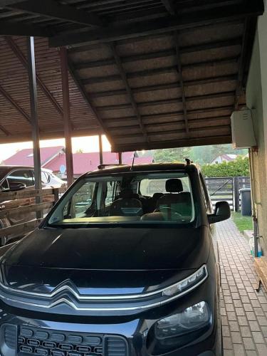 un coche aparcado debajo de un edificio con techo en Casa del bosque, en Upesciems