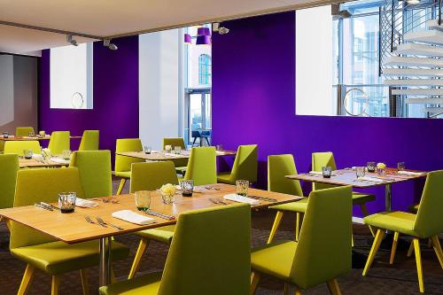a dining room with wooden tables and green chairs at Sheraton Hannover Pelikan Hotel in Hannover