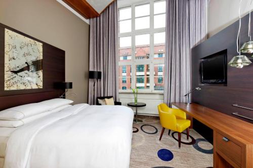 a hotel room with a bed and a desk and a tv at Sheraton Hannover Pelikan Hotel in Hannover