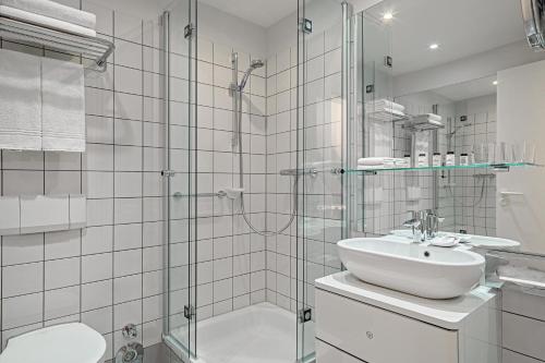 a bathroom with a glass shower and a sink at Sheraton Hannover Pelikan Hotel in Hannover