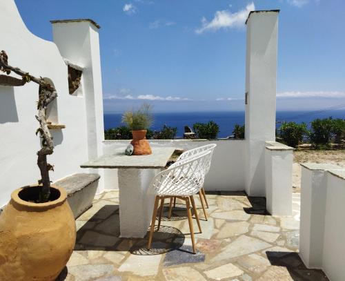 a patio with a table and chairs and the ocean at La Vista TINOS in Agios Ioannis Tinos